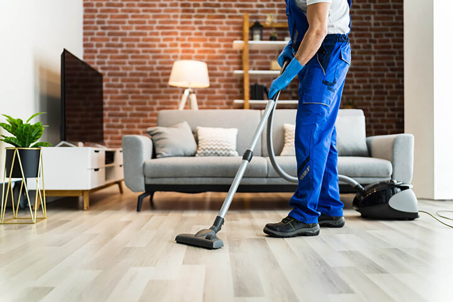 Professional cleaner vacuuming living room floor during standard cleaning vs deep cleaning service comparison