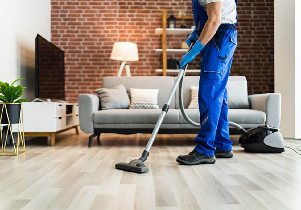 Professional cleaner vacuuming living room floor during standard cleaning vs deep cleaning service comparison